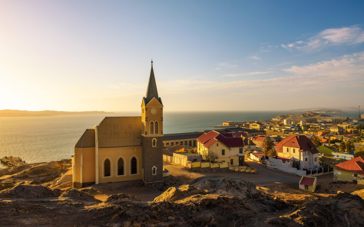 Panoramic view of Luderitz in Namibia at sunset with lutheran church called Felsenkirche and atlantic ocean in the background.